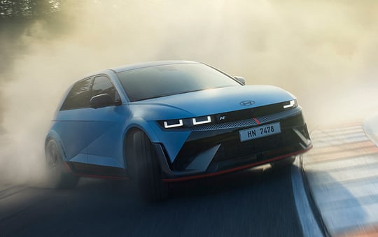 A blue Hyundai Ioniq 5 N driving through a smoky track corner