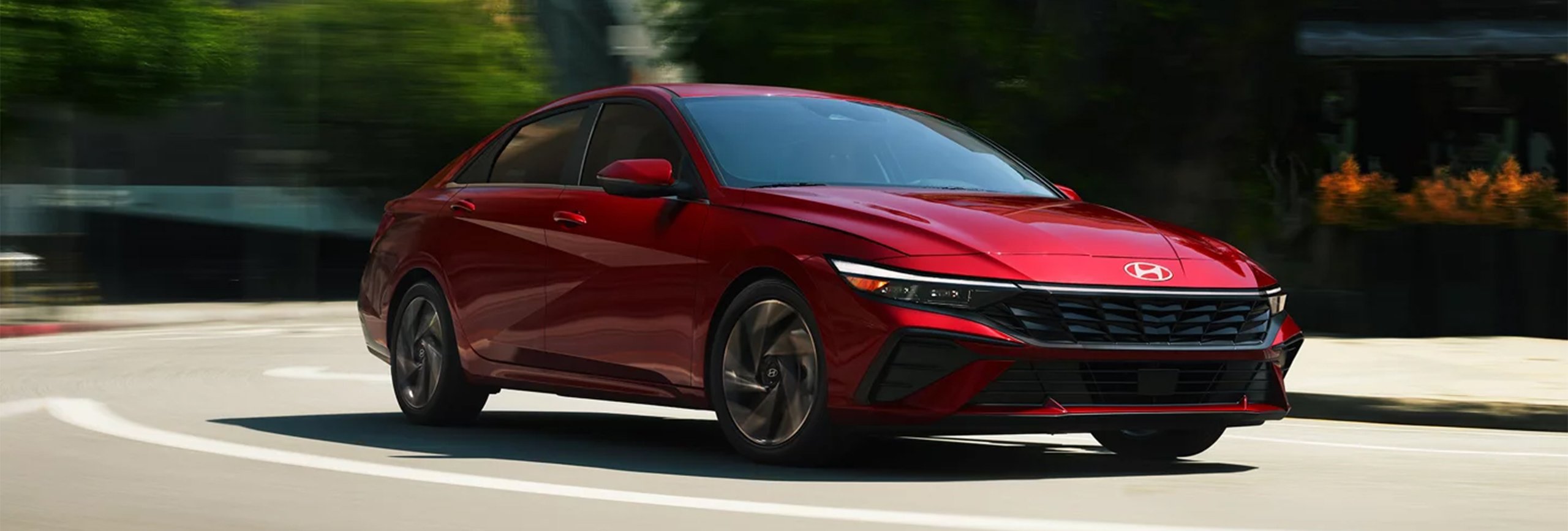 Vue 3/4 avant et latérale du Hyundai Elantra 2026 en pleine puissance sur route une journée d'été