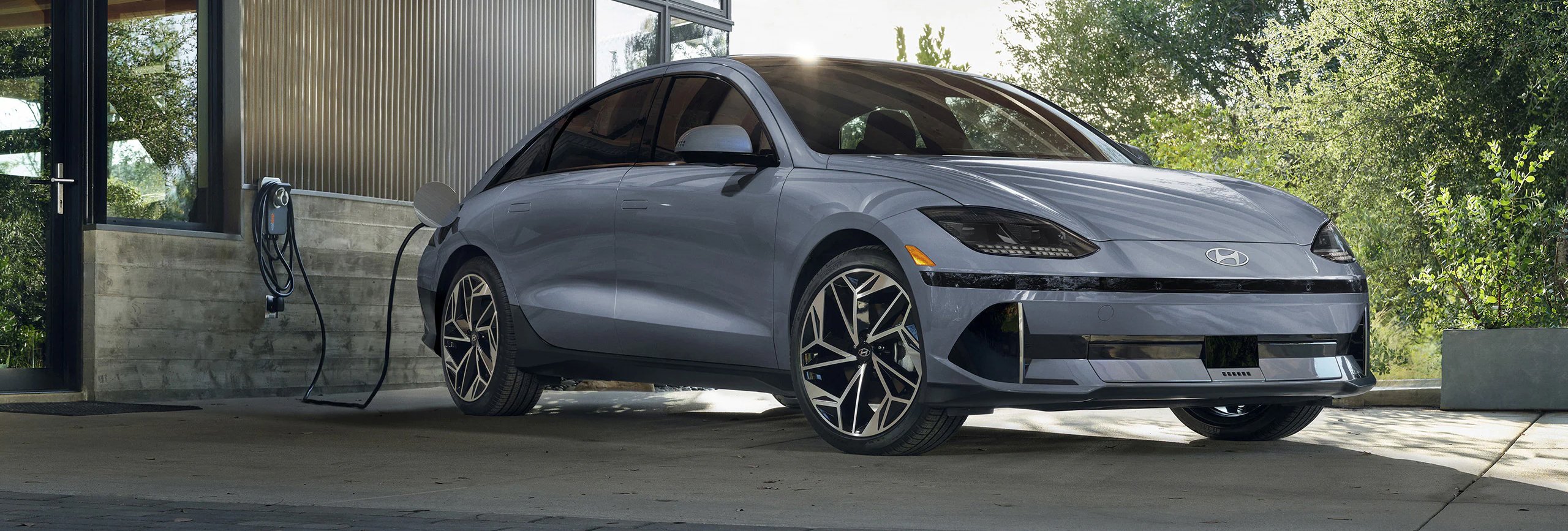 Vue 3/4 avant du Hyundai Ioniq 6 2026 en arrêt devant une maison en rechargement