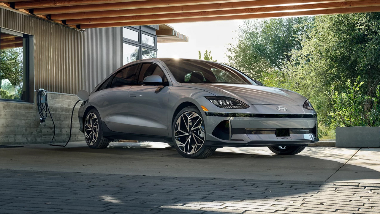 Vue 3/4 avant et latérale du Hyundai Ioniq 6 en arrêt sur une cour pavé et en rechargement