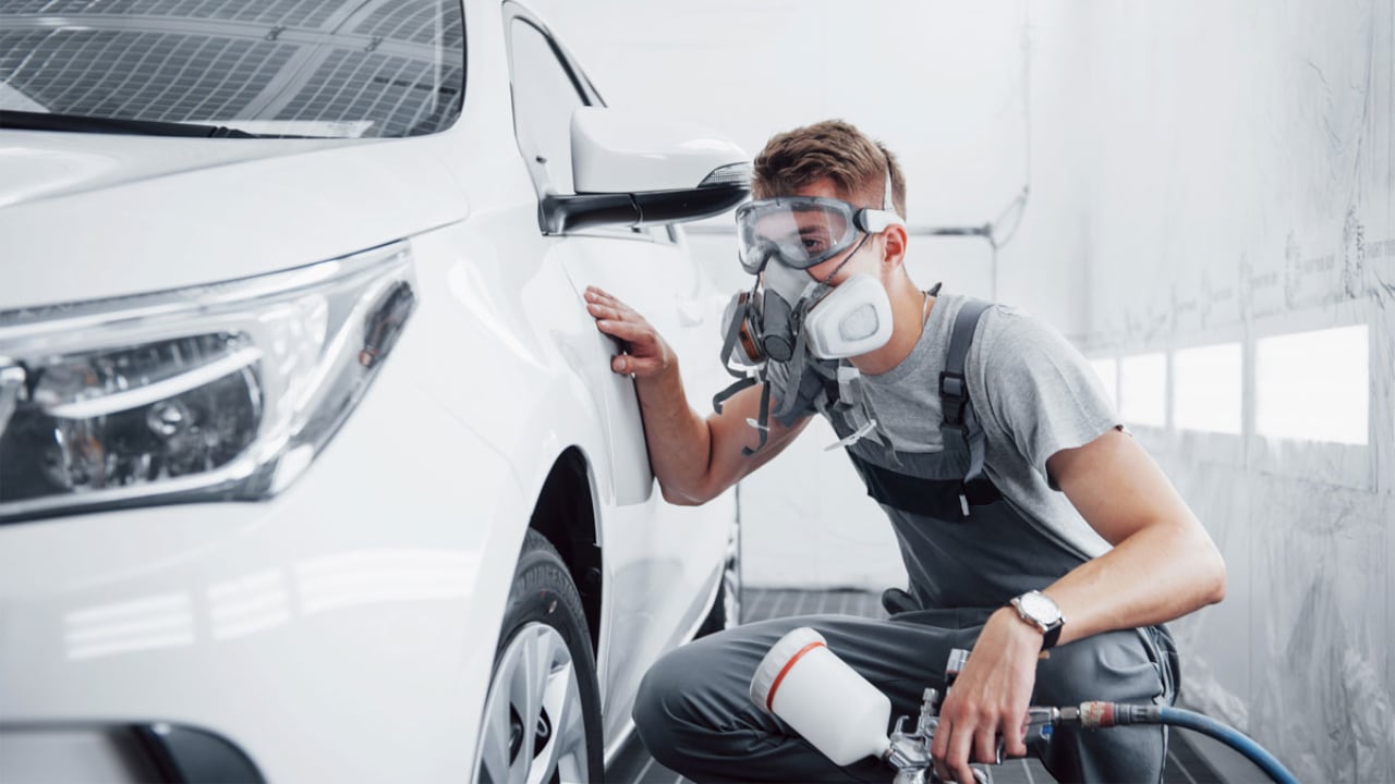 technicien en train de travailler sur la peinture d'un véhicule